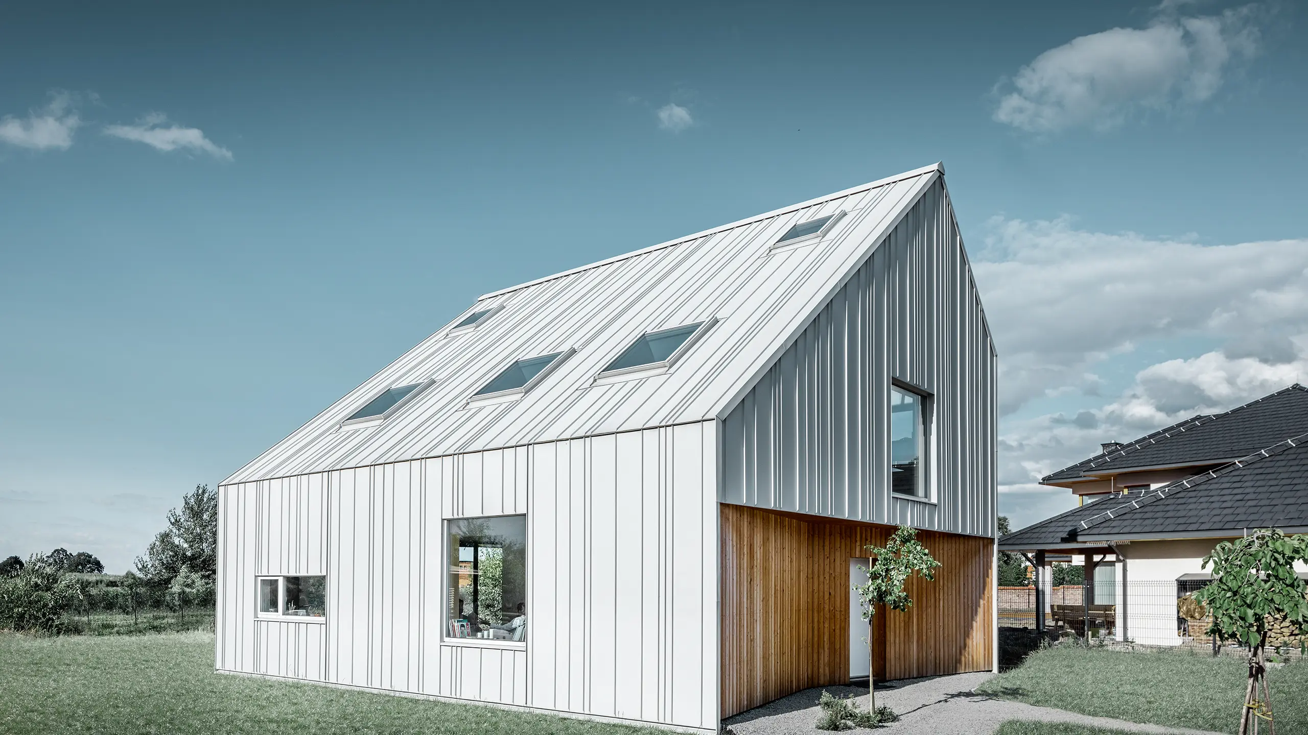 Casă monofamilială cu aspect modern, cu acoperiș cu două ape, întregul înveliș exterior este realizat cu PREFALZ în culoarea Alb prefa. Aici, îmbinările cu lățimi diferite se întind de la acoperiș, mai departe pe fațadă. În acoperiș sunt instalate mai multe geamuri de acoperiș.