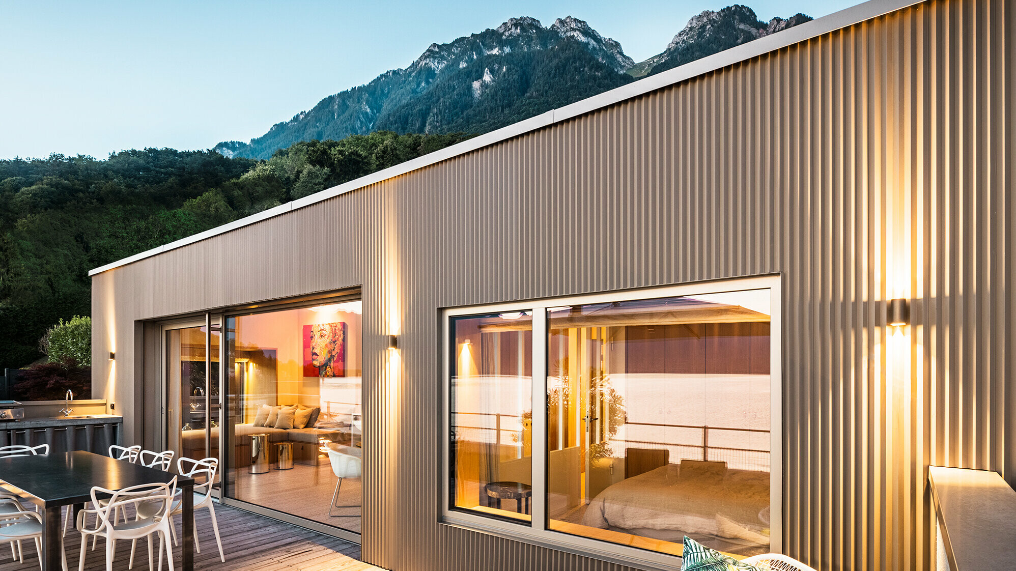 Vedere spre terasă și o parte din interiorul clădirii seara.