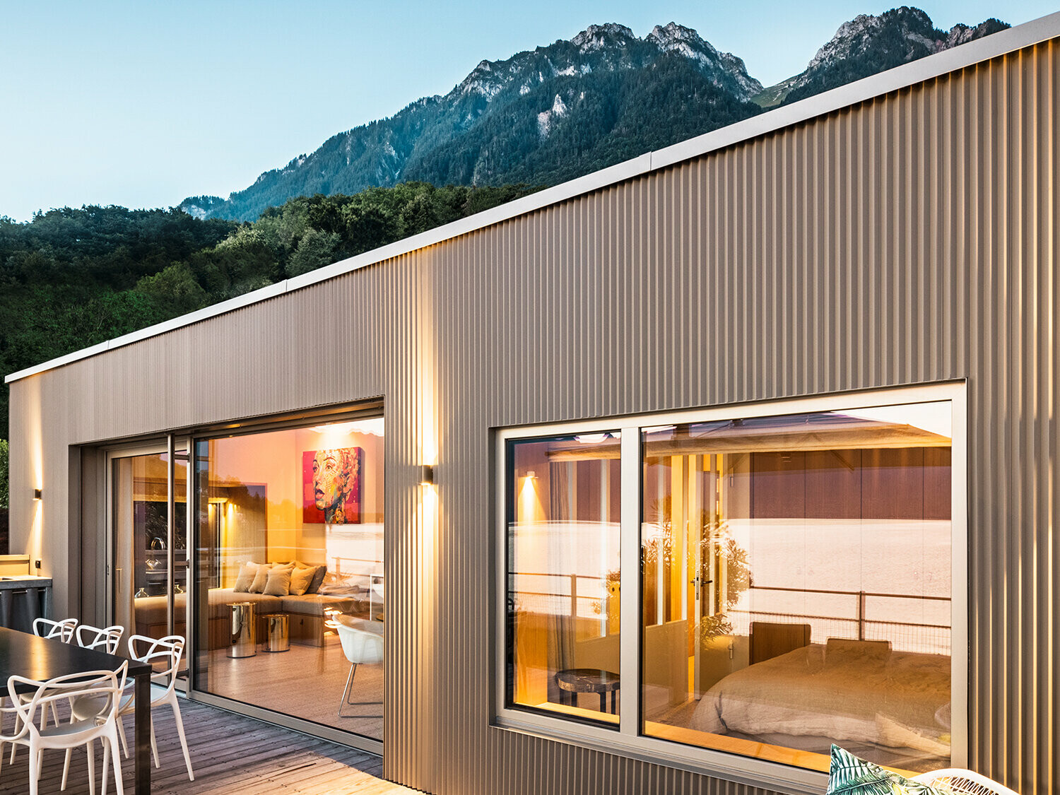 Vedere spre terasă și o parte din interiorul clădirii seara.