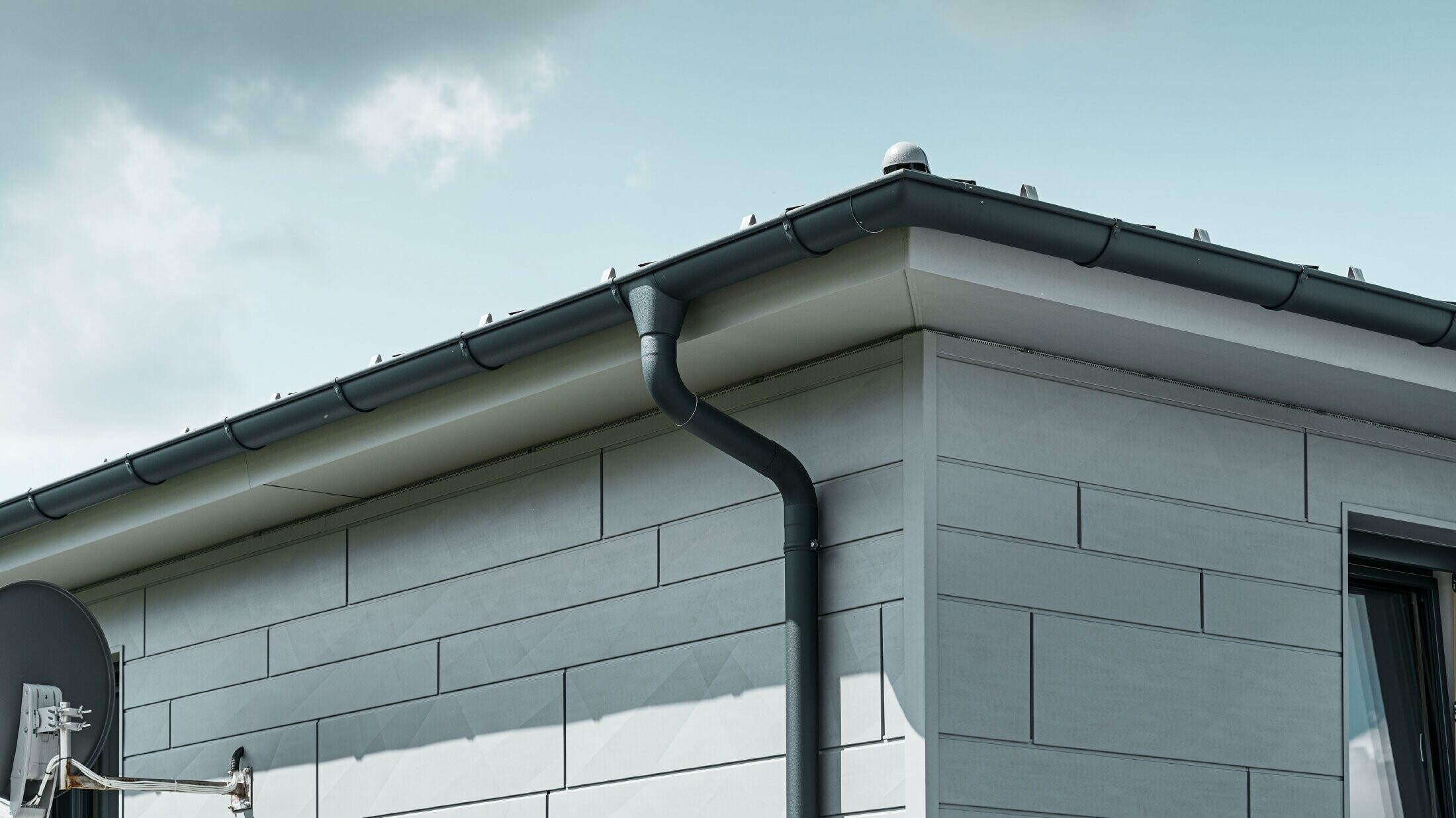 Sageac cu jgheab PREFA, racord de burlan și burlan în culoarea antracit cu fațadă PREFA Siding.X în culoarea gri patinat