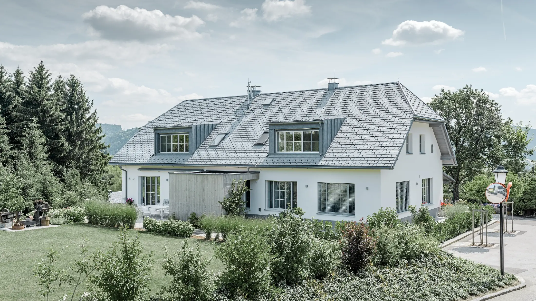 Gaube des neu sanierten Einfamilienhauses mit der PREFA Dachschindel in Steingrau. Die Gaube ist mit Prefalz (Stehfalz) verkleidet.