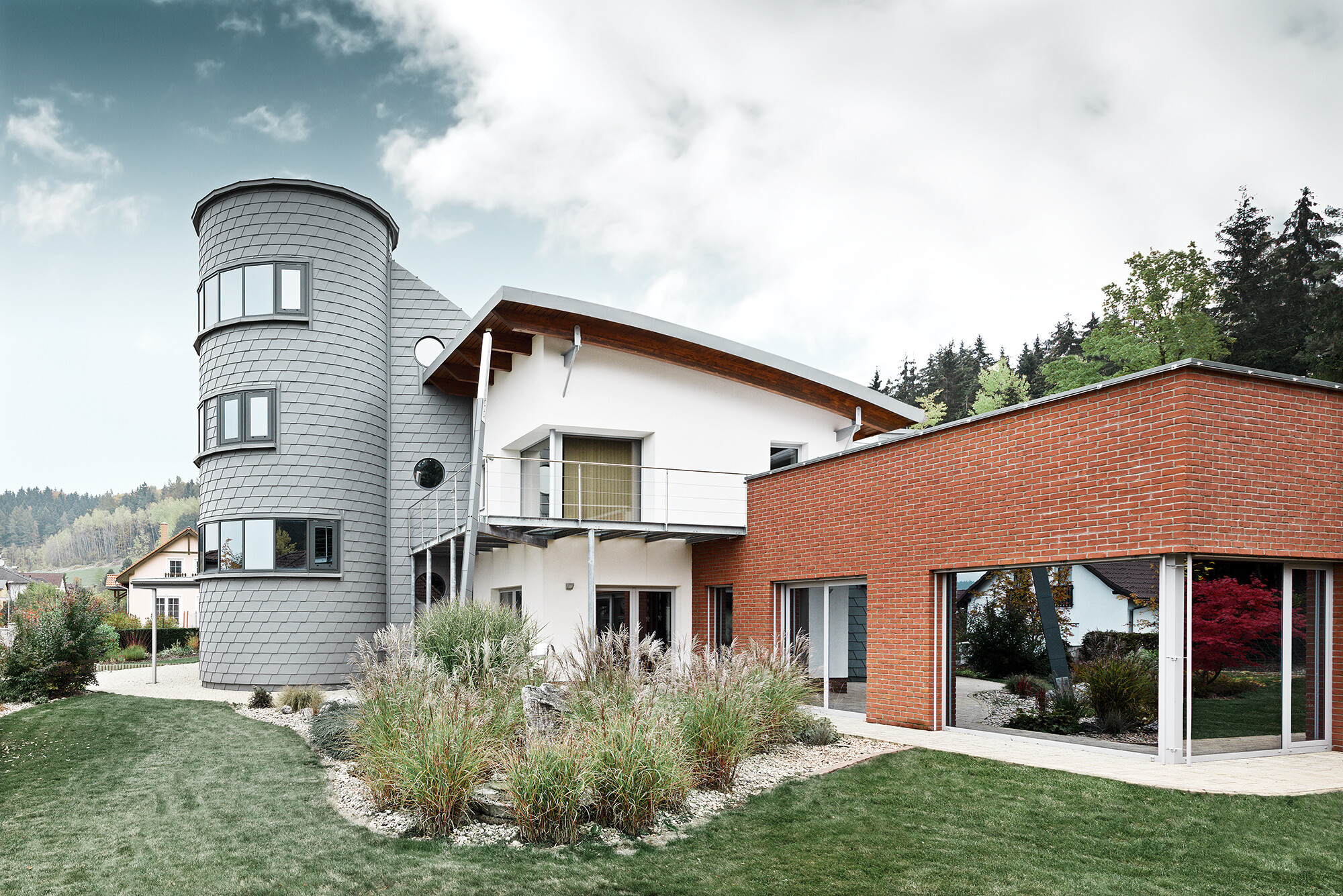 Casă monofamilială cu turn, turnul rotund este placat cu solizii pentru fațade PREFA în culoarea gri patinat 