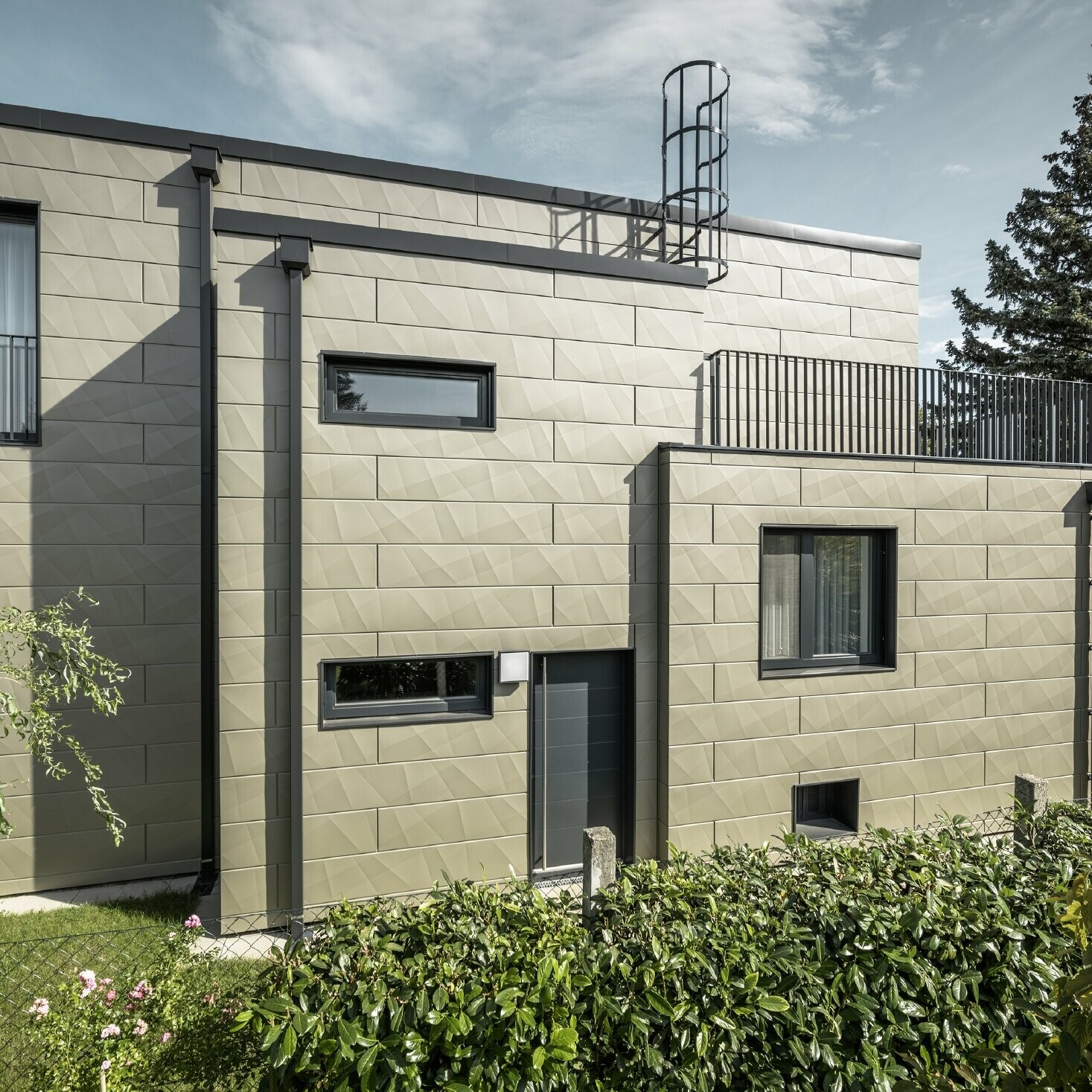 Clădire nouă cu acoperiș plat, fațada este acoperită cu panouri de fațadă Siding.X PREFA cu margini în bronz, ramele, precum și țeava de scurgere pătrată, țeava pătrată PREFA sunt realizate în antracit.