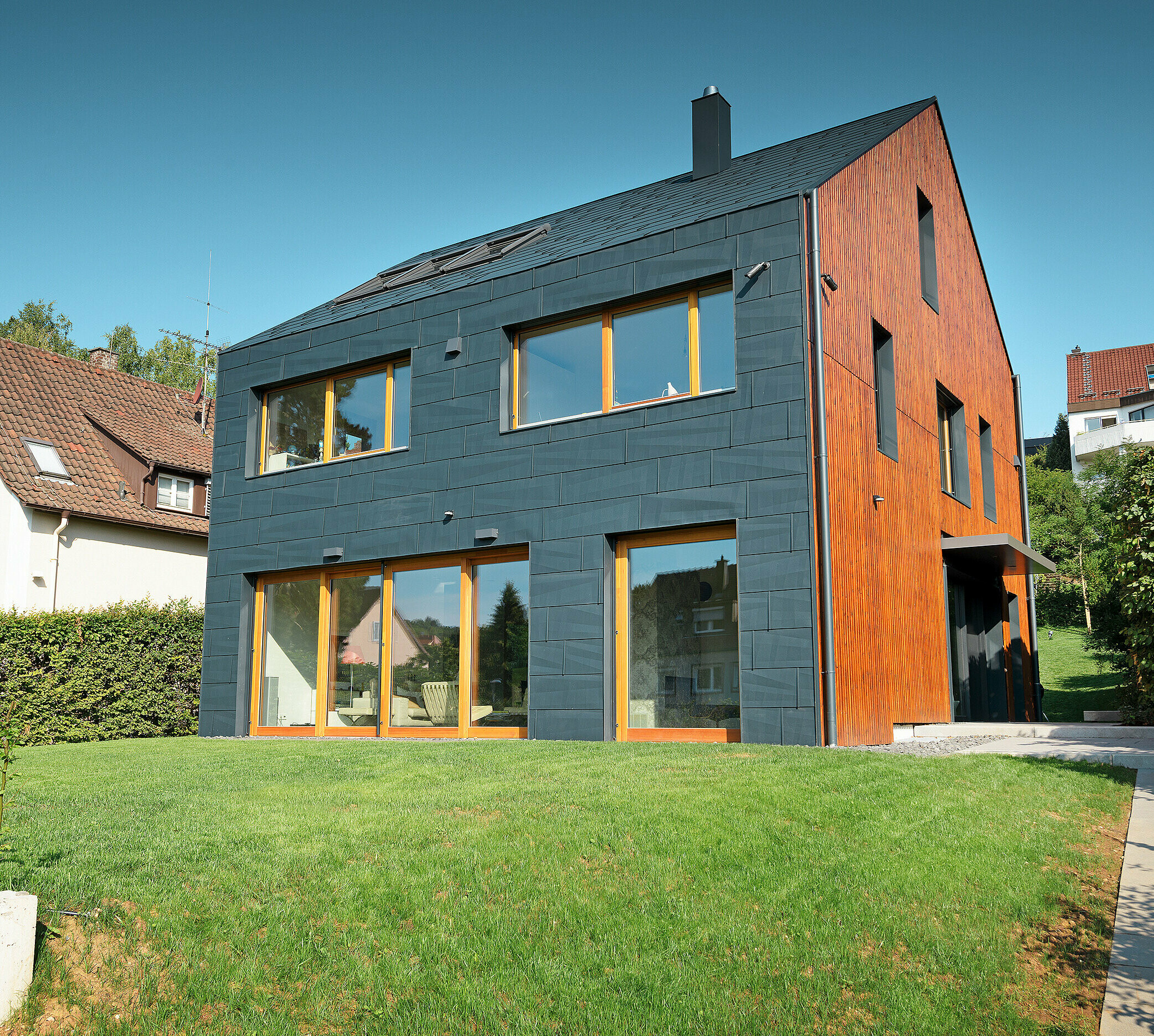 Fațada PREFA FX.12 în culoarea P.10 antracit trece de pe fațadă pe acoperișul cu două ape complet fără streașină.