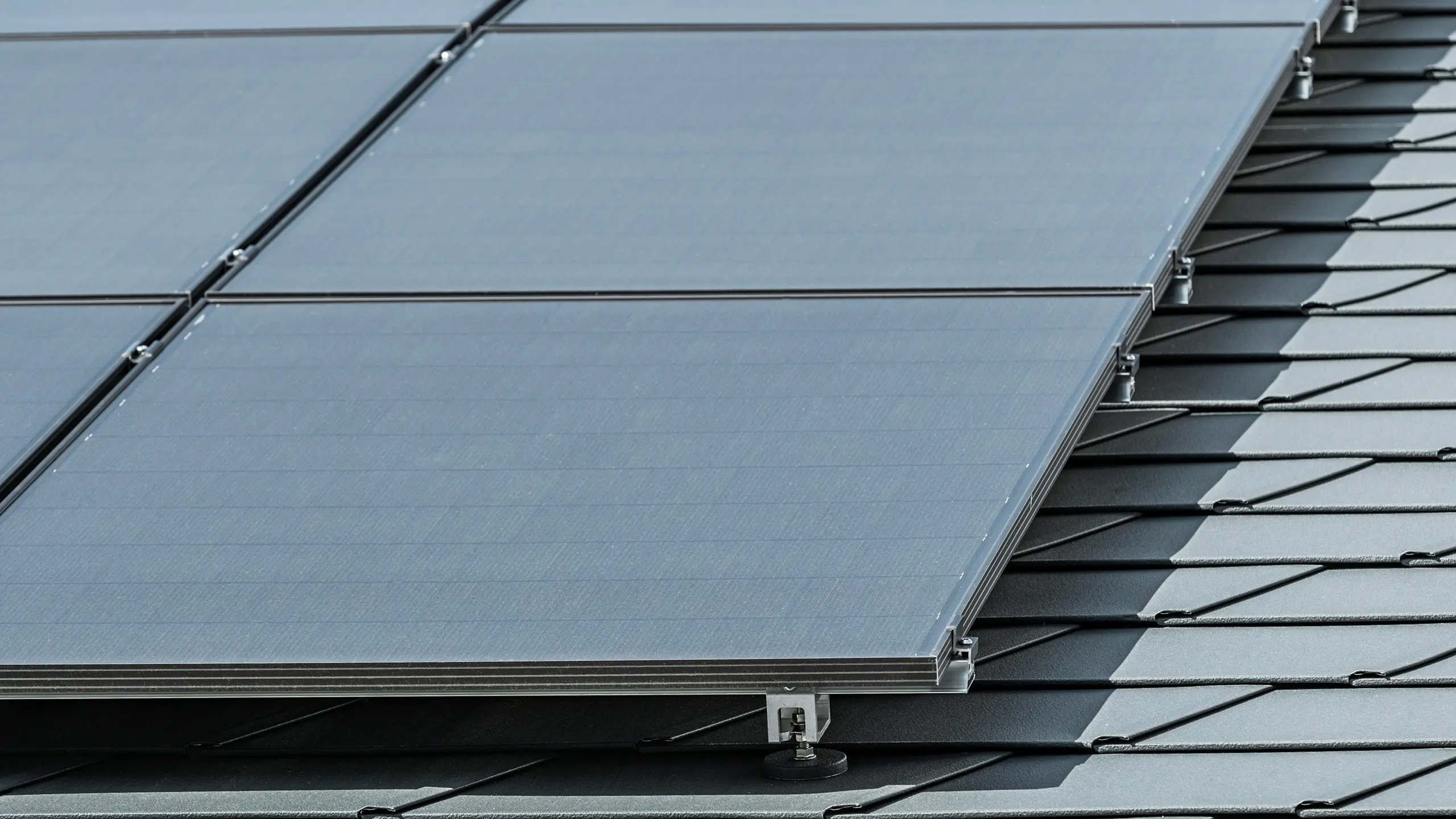 Imagine de detaliu a unei instalații fotovoltaice pe șindrilă PREFA DS.19 în culoarea P.10 antracit, montată cu suportul solar PREFA Vario
