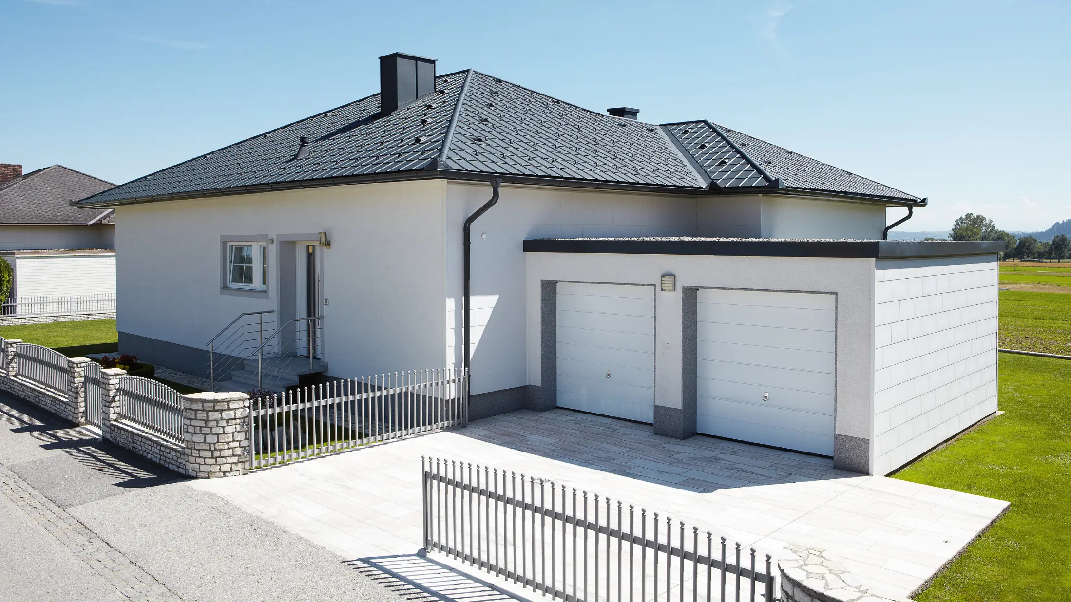 Bungaloul nou construit cu acoperiș piramidal a fost acoperit cu placa classic PREFA în culoarea P.10 antracit. În dreapta a fost construit un garaj dublu, fotografia a fost realizată din stradă.