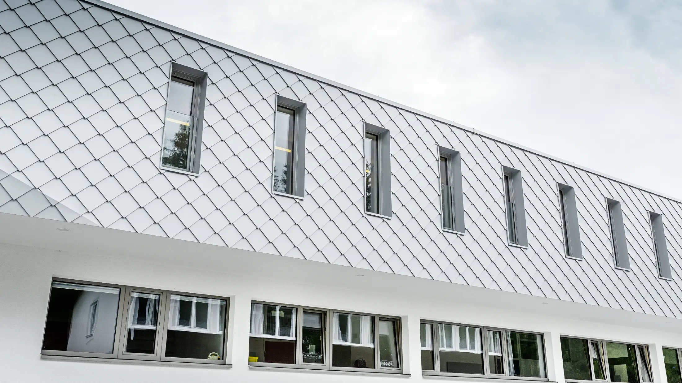 Grădiniță nou construită în Kaprun cu o fațadă modernă din aluminiu, cu solzii romboidali pentru fațade PREFA în culoarea alb Prefa