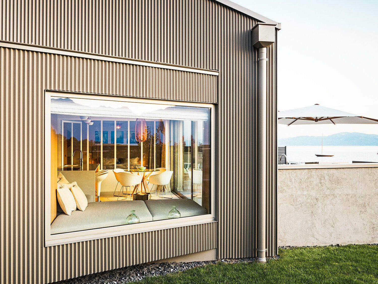 Vedere laterală a clădirii cu fațadă din aluminiu zimțat, este vizibilă și o parte din interiorul iluminat.