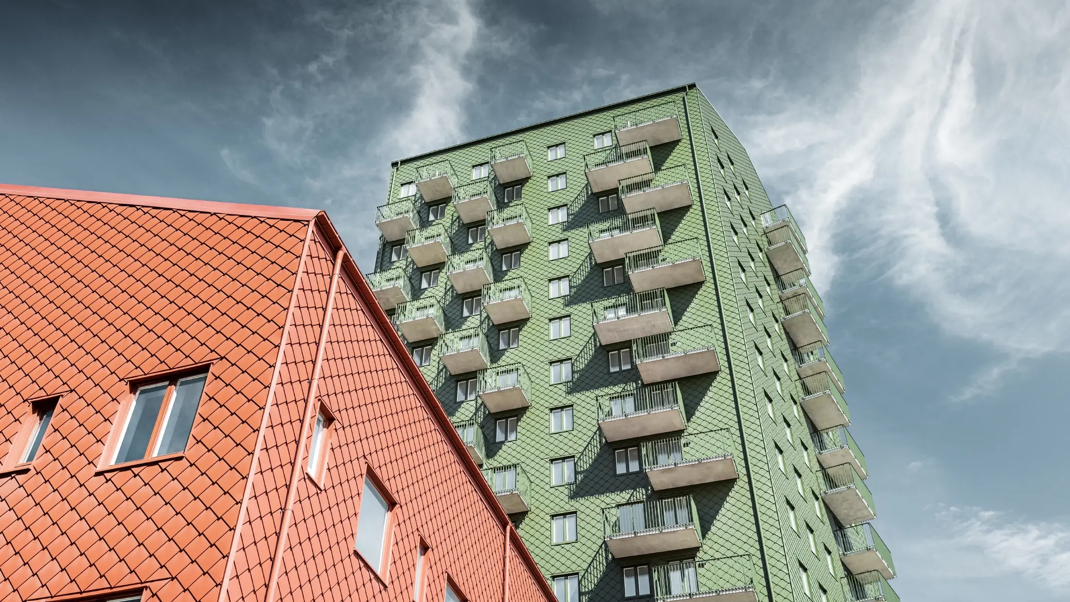 Blocuri cu balcoane cu designul fațadei cu solzi romboidali PREFA 29 x 29 în culorile verde oliv și roșu cărămiziu