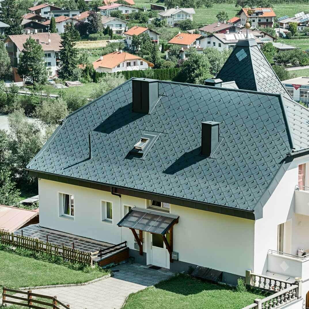 Krüppelwalmdach mit einem Turm, eingedeckt mit der Aluminium Dachraute 44 × 44 in Anthrazit.