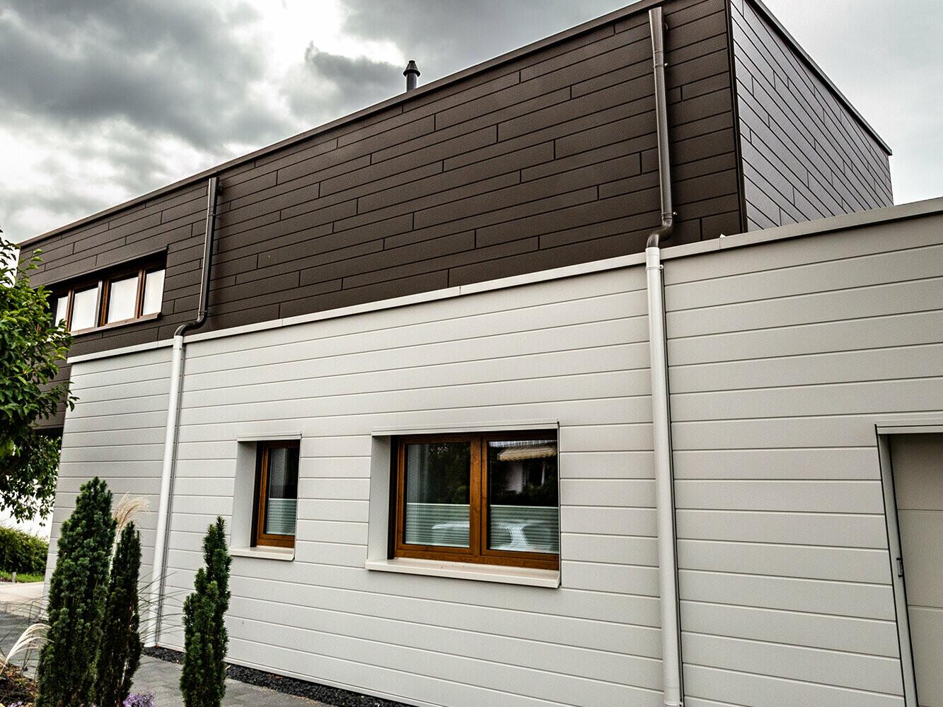 Combinație de panouri de fațadă PREFA în culorile maro și Alb Prefa cu burlanul PREFA în culori asortate incl. racord pentru atic.