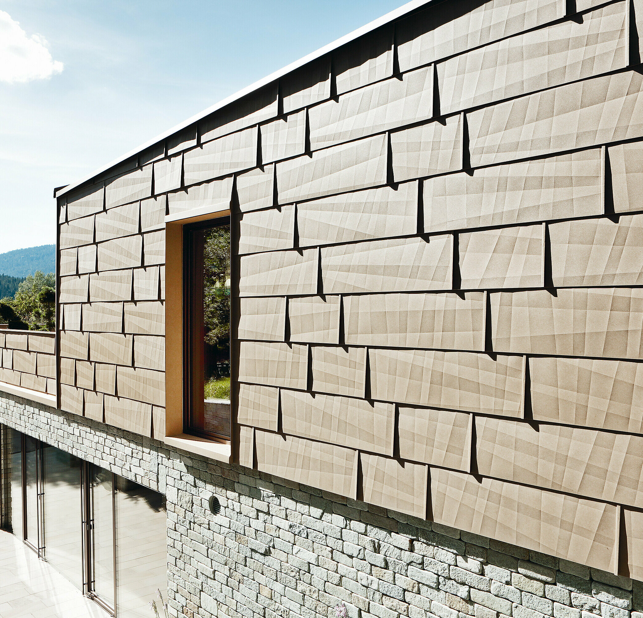 Pe această fațadă exterioară a fost combinat panoul pentru fațade FX.12 PREFA în culoarea P.10 maro nisip cu o fațadă din piatră la demisol.