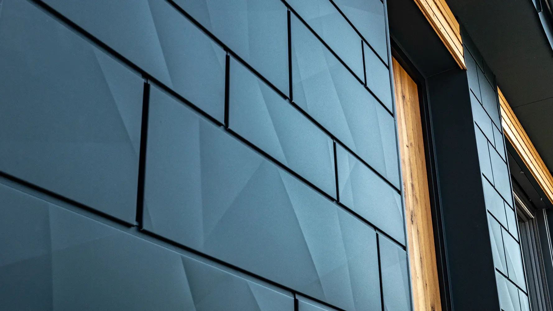 Panourile pentru fațade PREFA cu aspect îndoit; PREFA Siding.X din aluminiu în culoarea antracit combinat cu fațadă din lemn.